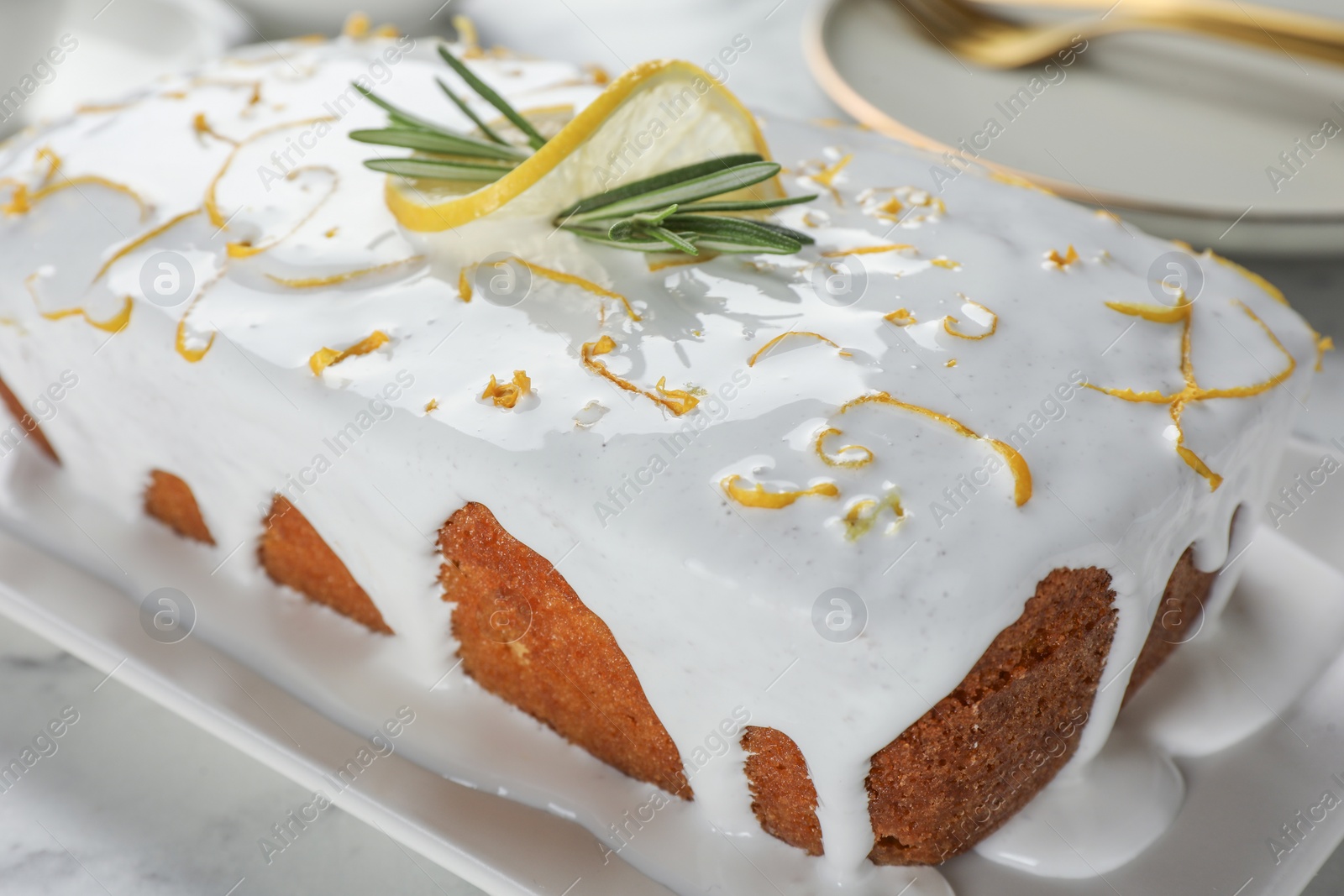 Photo of Tasty lemon cake with glaze and rosemary on table, closeup