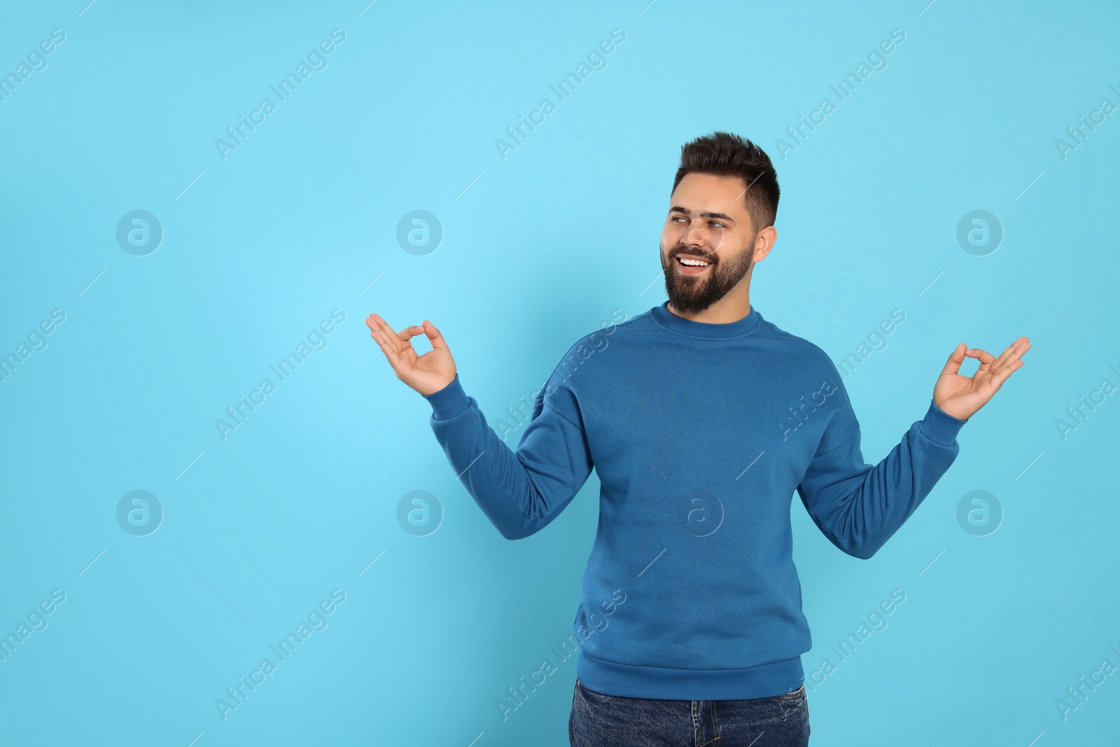 Photo of Young man meditating on light blue background. Zen concept