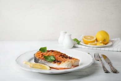 Plate with tasty salmon steak on wooden table