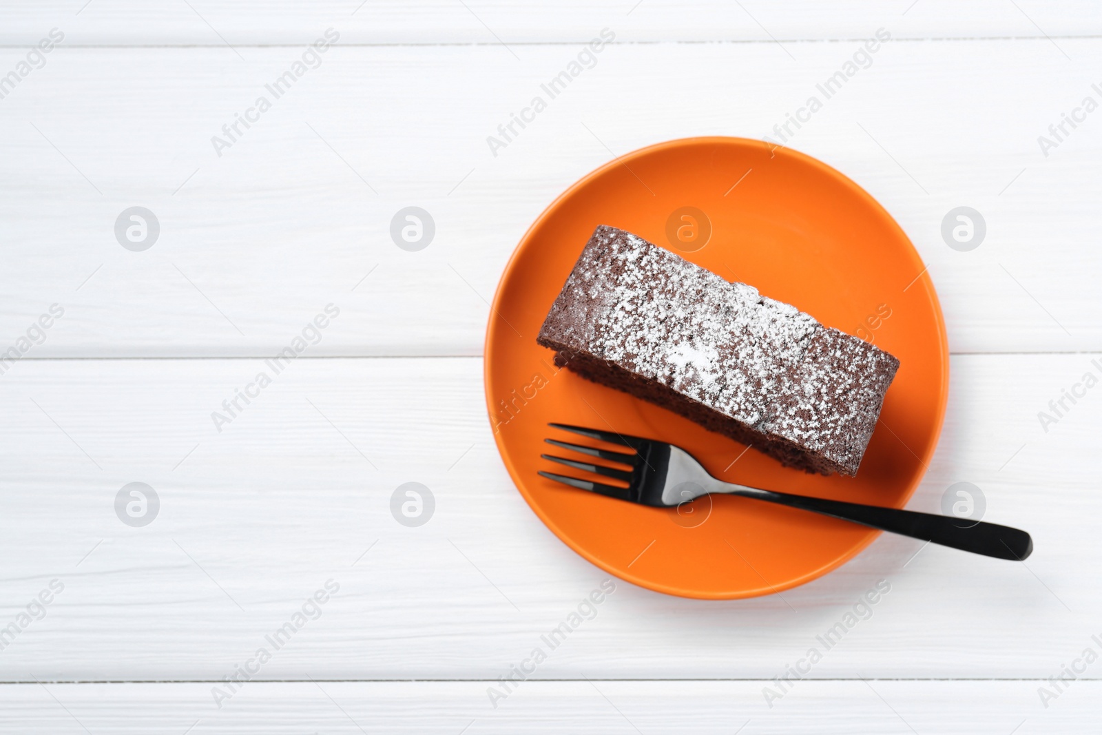 Photo of Piece of tasty chocolate sponge cake with powdered sugar on white wooden table, top view. Space for text