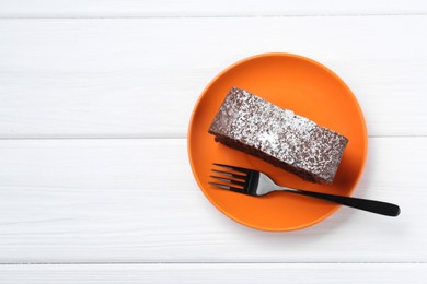 Piece of tasty chocolate sponge cake with powdered sugar on white wooden table, top view. Space for text