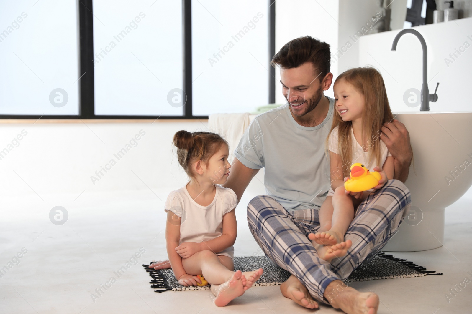 Photo of Father with little daughters near tub in bathroom