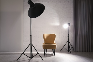 Photo of Interior of modern photo studio with professional lighting equipment and armchair