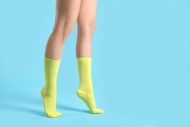 Photo of Woman in stylish yellow socks on light blue background, closeup. Space for text