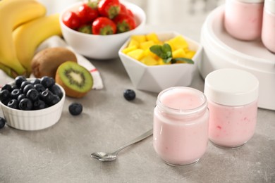 Photo of Jars with yogurt and different fruits on light grey table