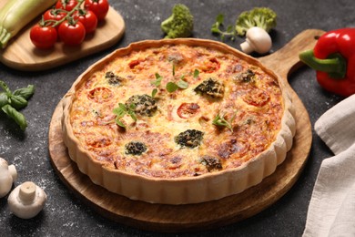 Photo of Delicious homemade vegetable quiche, oregano and mushrooms on black table