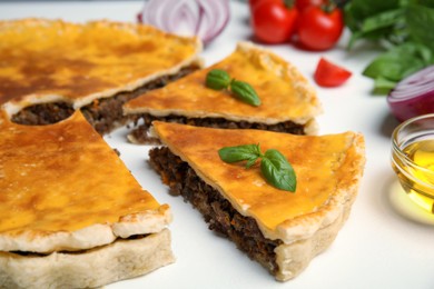 Delicious pie with minced meat and basil on white table, closeup