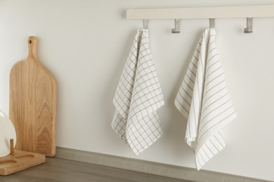 Photo of Different kitchen towels hanging on hook rack indoors