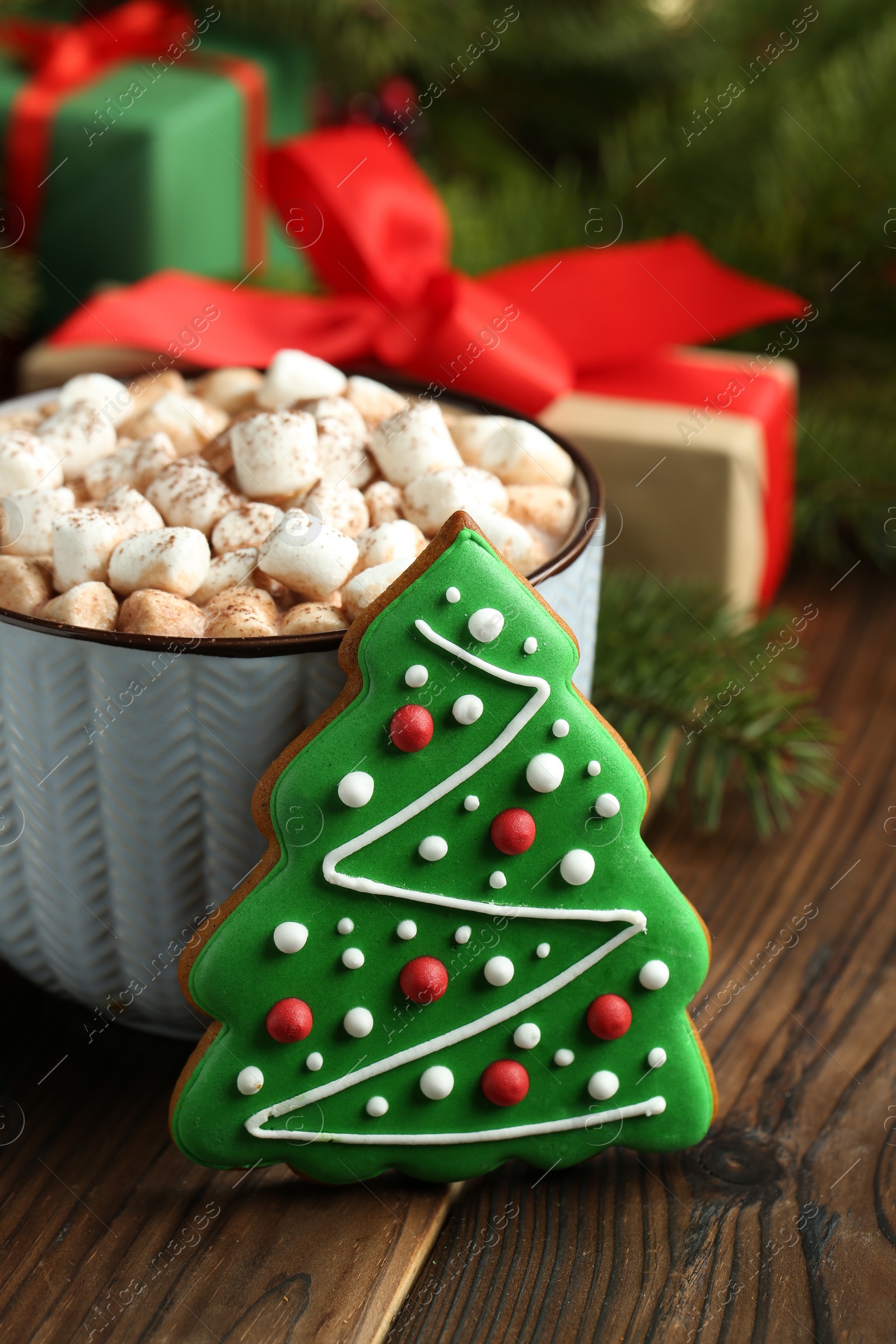 Photo of Tasty Christmas cookie in shape of fir tree and cocoa with marshmallows on wooden table, closeup
