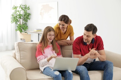 Parents and their teenager daughter with laptop computer at home