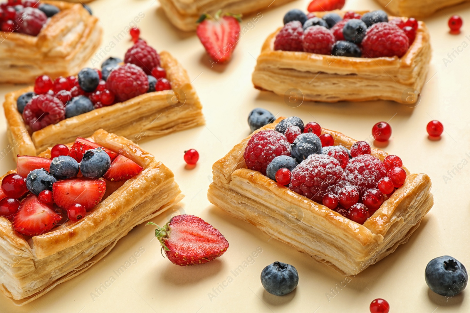 Photo of Fresh delicious puff pastry with sweet berries on beige background, closeup