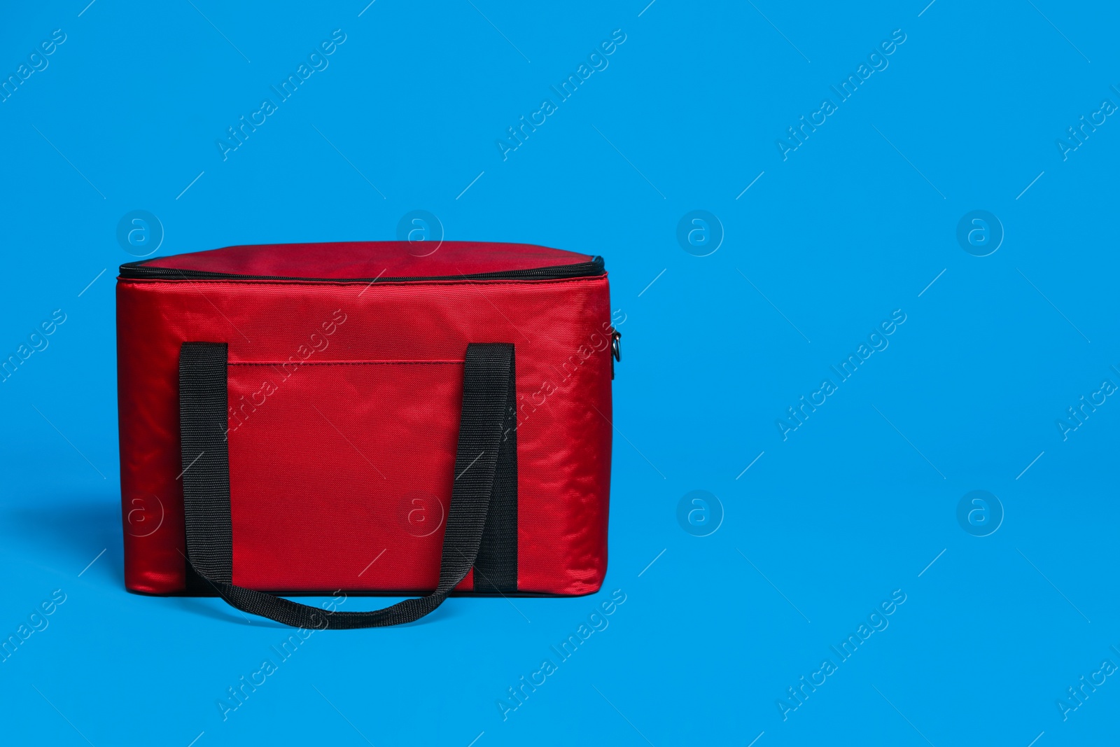 Photo of Modern red thermo bag on light blue background. Space for text