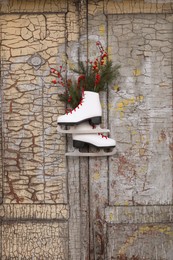 Photo of Pair of ice skates with Christmas decor hanging on old wooden door