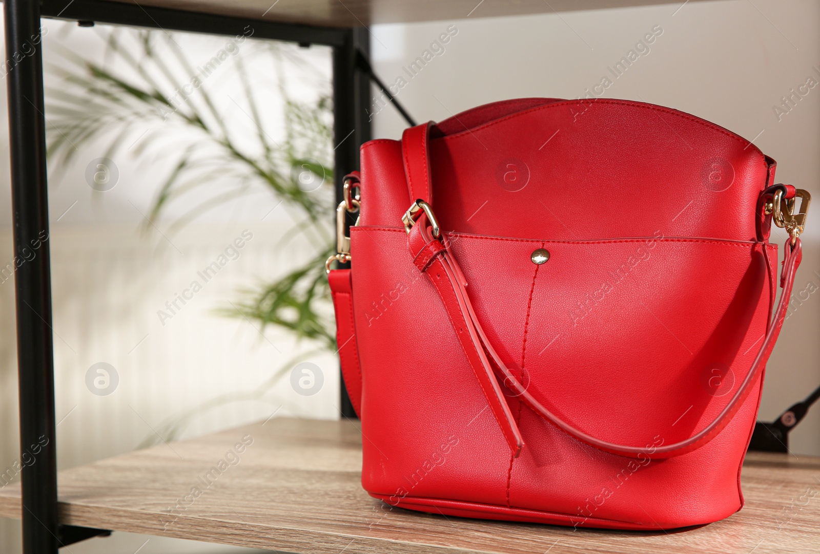Photo of Stylish red woman's bag on wooden shelf