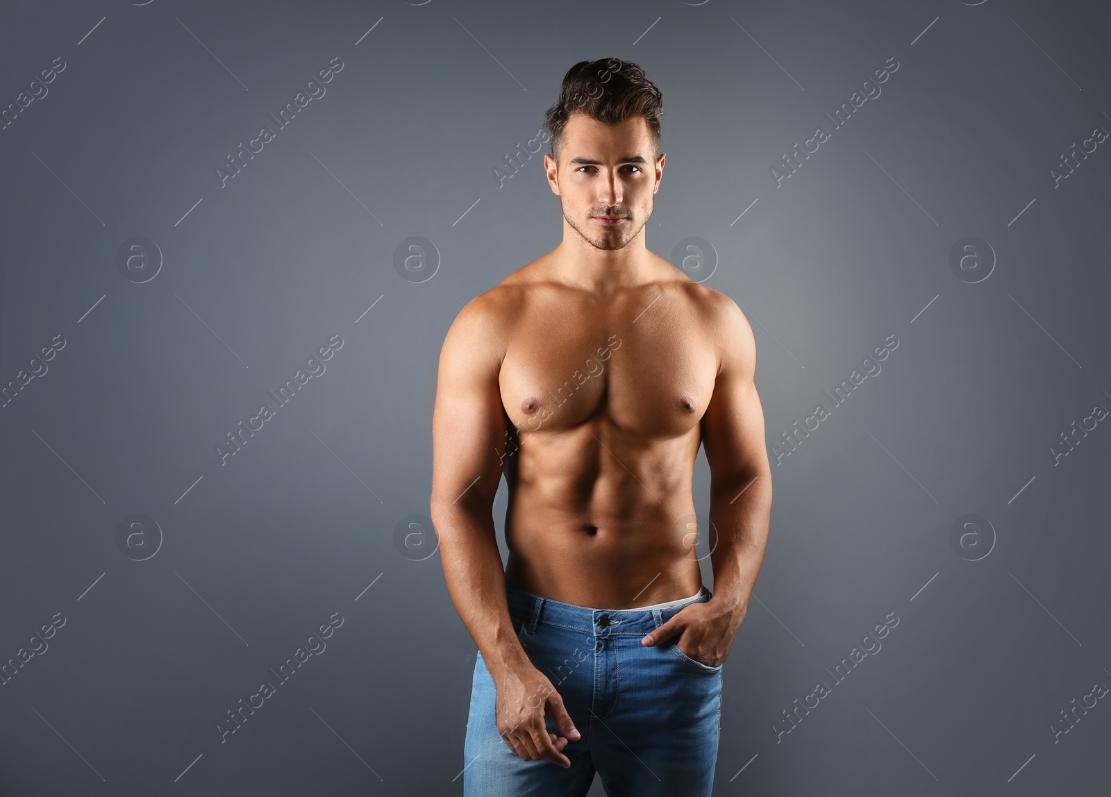 Photo of Shirtless young man in stylish jeans on grey background