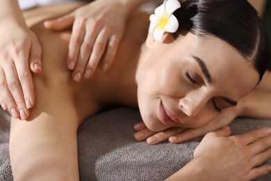 Spa therapy. Beautiful young woman lying on table during massage in salon