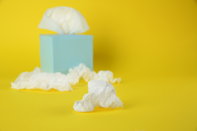 Photo of Used paper tissues and box on yellow background. Space for text