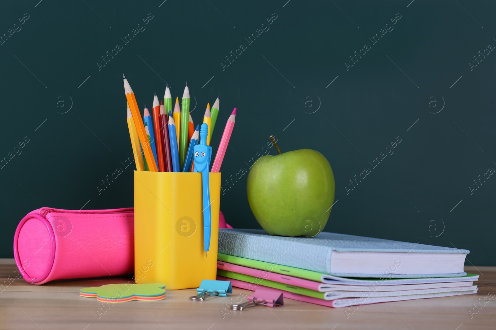 Photo of Composition with stationery and apple on table near chalkboard. Doing homework
