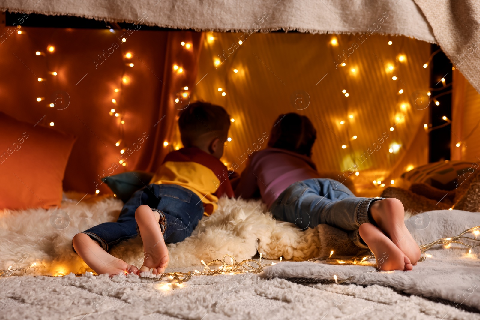 Photo of Kids in decorated play tent at home, back view