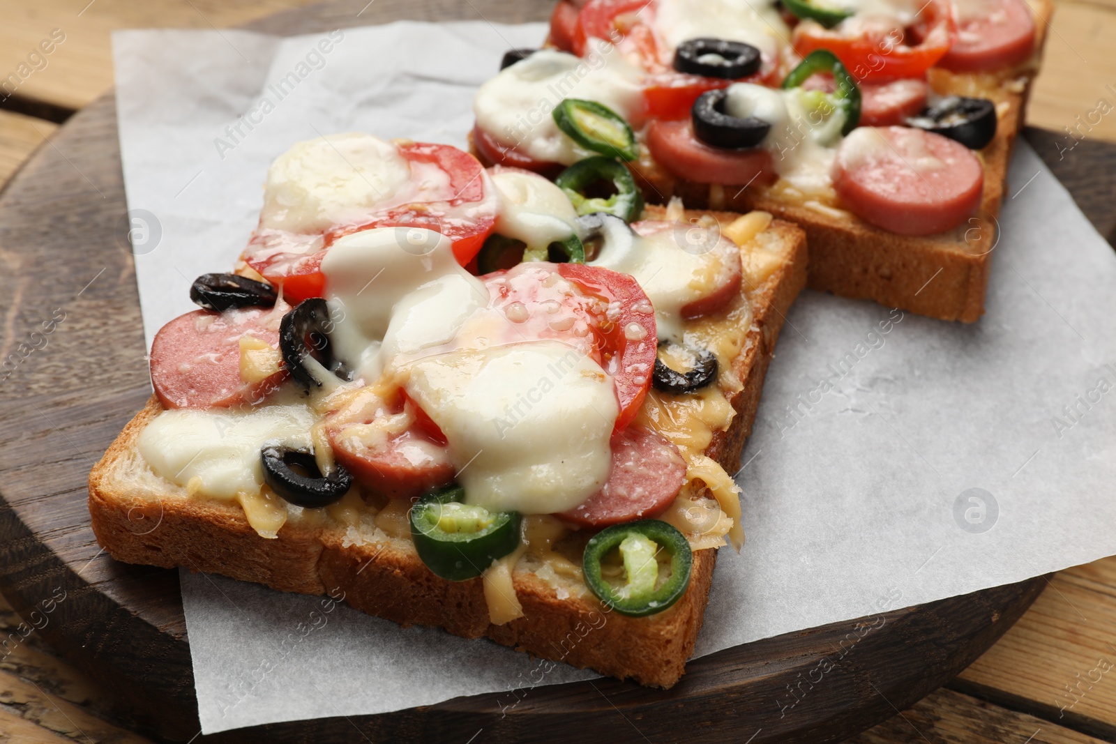 Photo of Tasty pizza toasts on wooden table, closeup