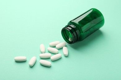 Vitamin pills and bottle on mint color background