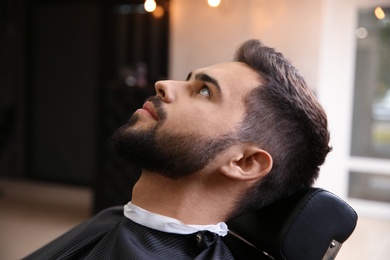 Photo of Young man visiting barbershop. Professional shaving service