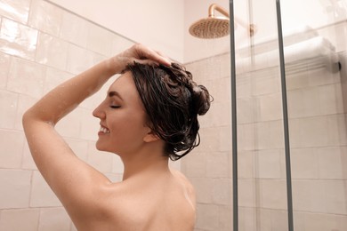 Happy woman washing hair while taking shower at home