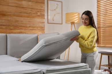 Young woman unfolding sofa into a bed in room. Modern interior