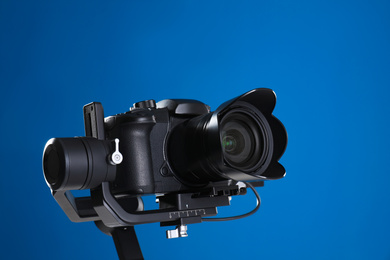 Photo of Modern professional video camera on blue background