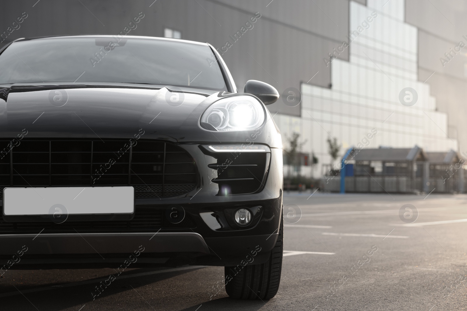 Photo of Modern black car parked on asphalt road outdoors at sunrise, space for text