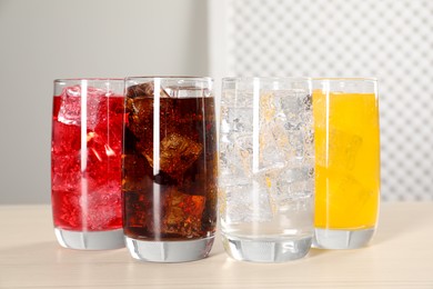 Photo of Glasses of different refreshing soda water with ice cubes on white table