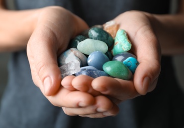 Photo of Woman holding pile of different gemstones, closeup