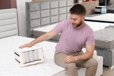 Smiling man with sample of orthopedic mattress in store