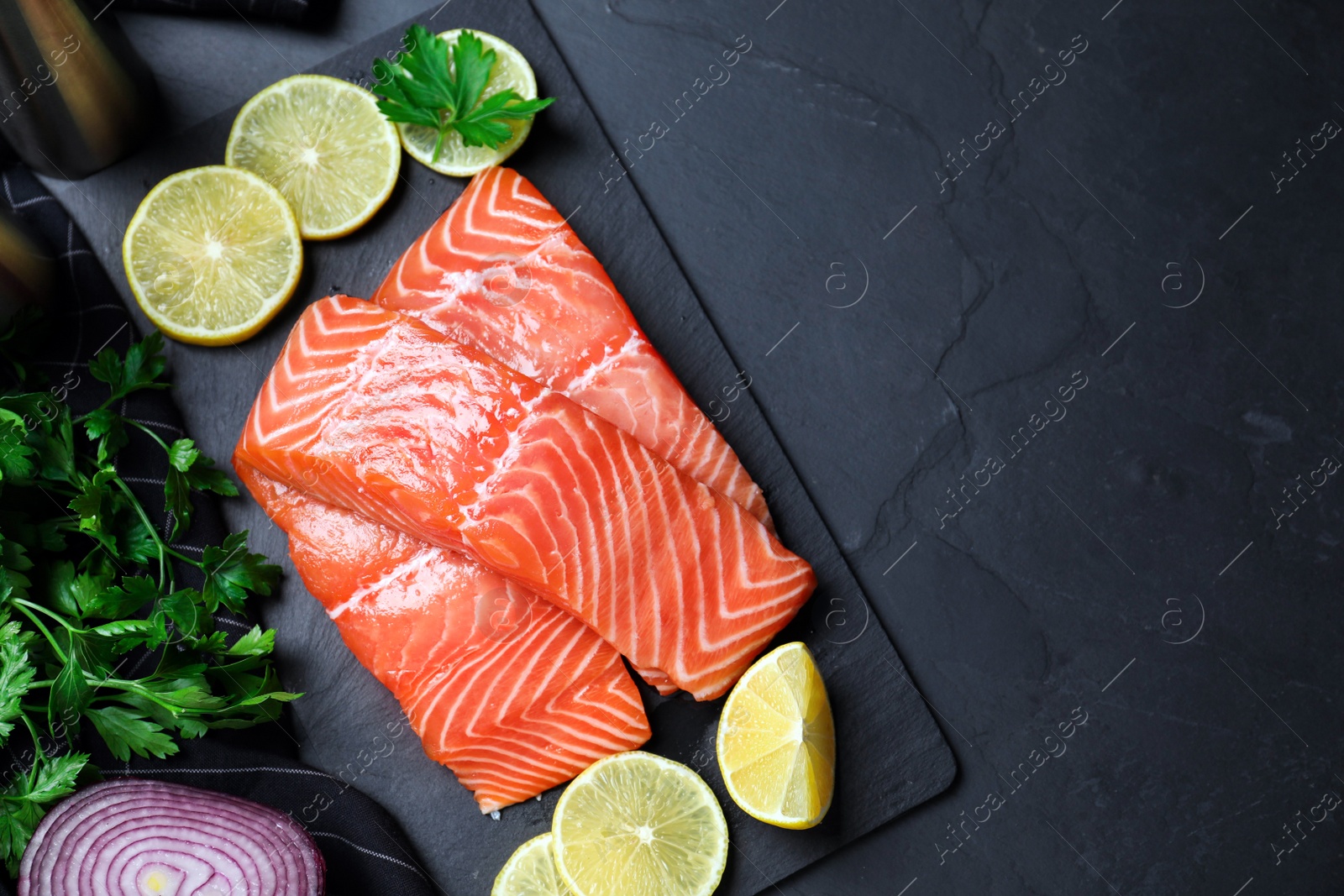 Photo of Flat lay composition with fresh raw salmon and products on black table, space for text. Fish delicacy