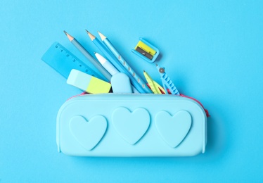 Photo of Pencil case and different stationery on light blue background, flat lay. Back to school