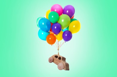 Image of Many balloons tied to wooden toy car flying on turquoise background