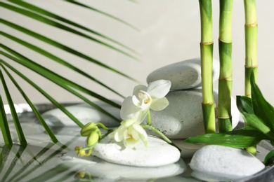 Photo of Spa stones, orchid and bamboo branches in water. Space for text