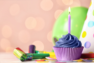 Photo of Delicious birthday cupcake with cream and burning candle on white table. Space for text