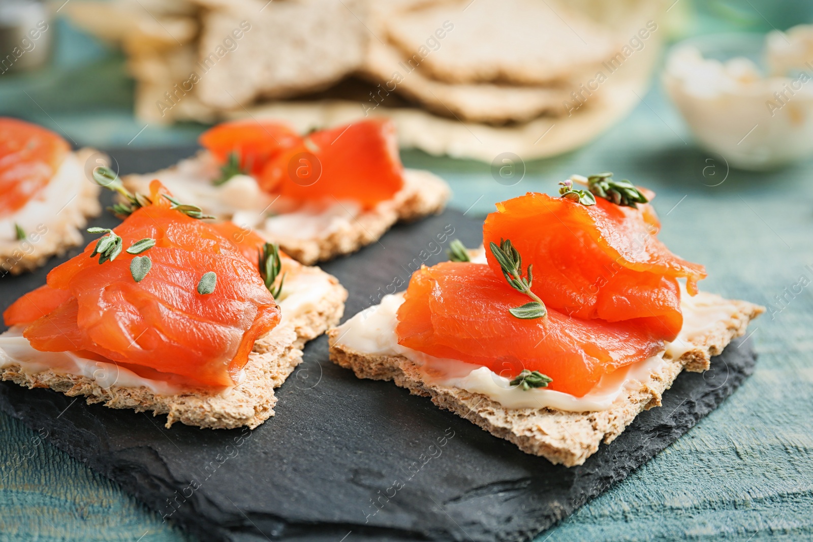 Photo of Crispbreads with fresh sliced salmon fillet on slate board