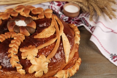 Fresh korovai on wooden table, closeup. Ukrainian bread and salt welcoming tradition