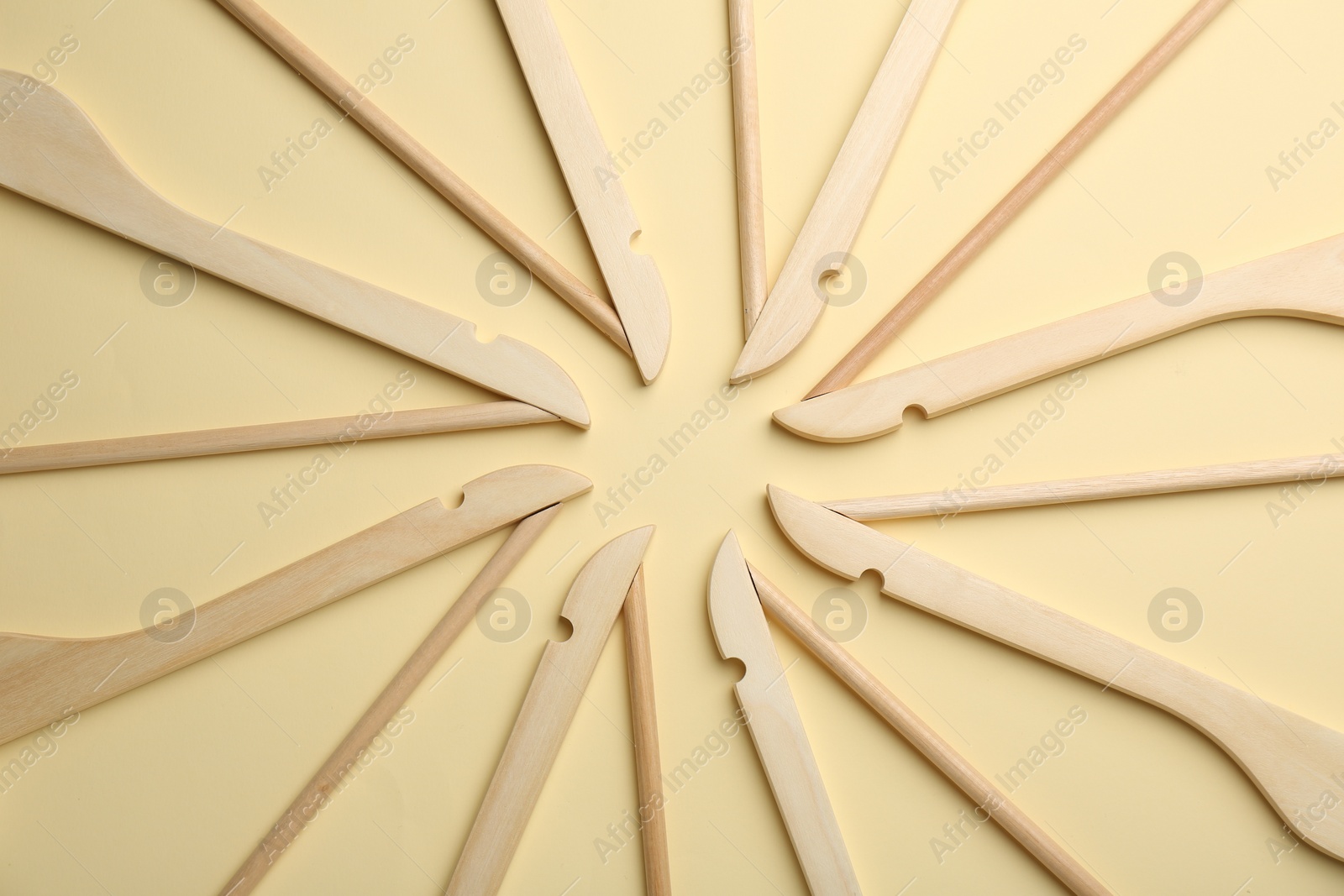 Photo of Wooden hangers on pale yellow background, flat lay