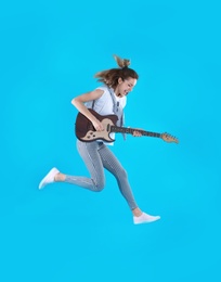 Photo of Young woman playing electric guitar on color background