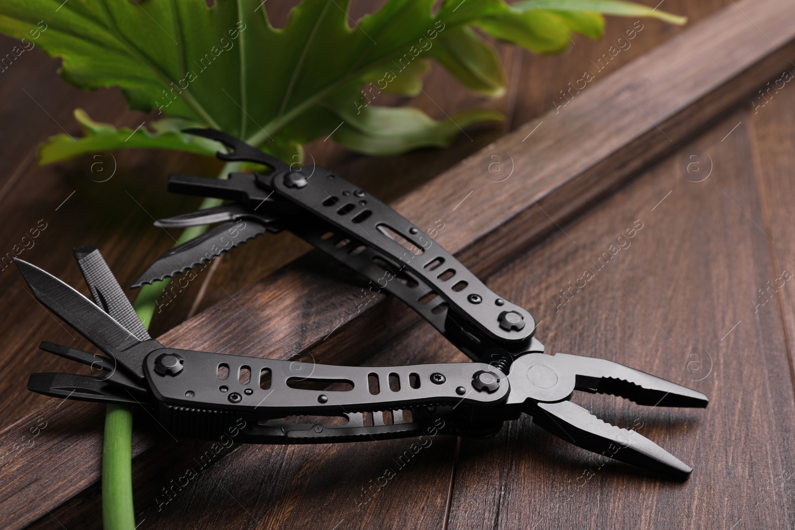 Photo of Modern compact portable multitool on wooden table