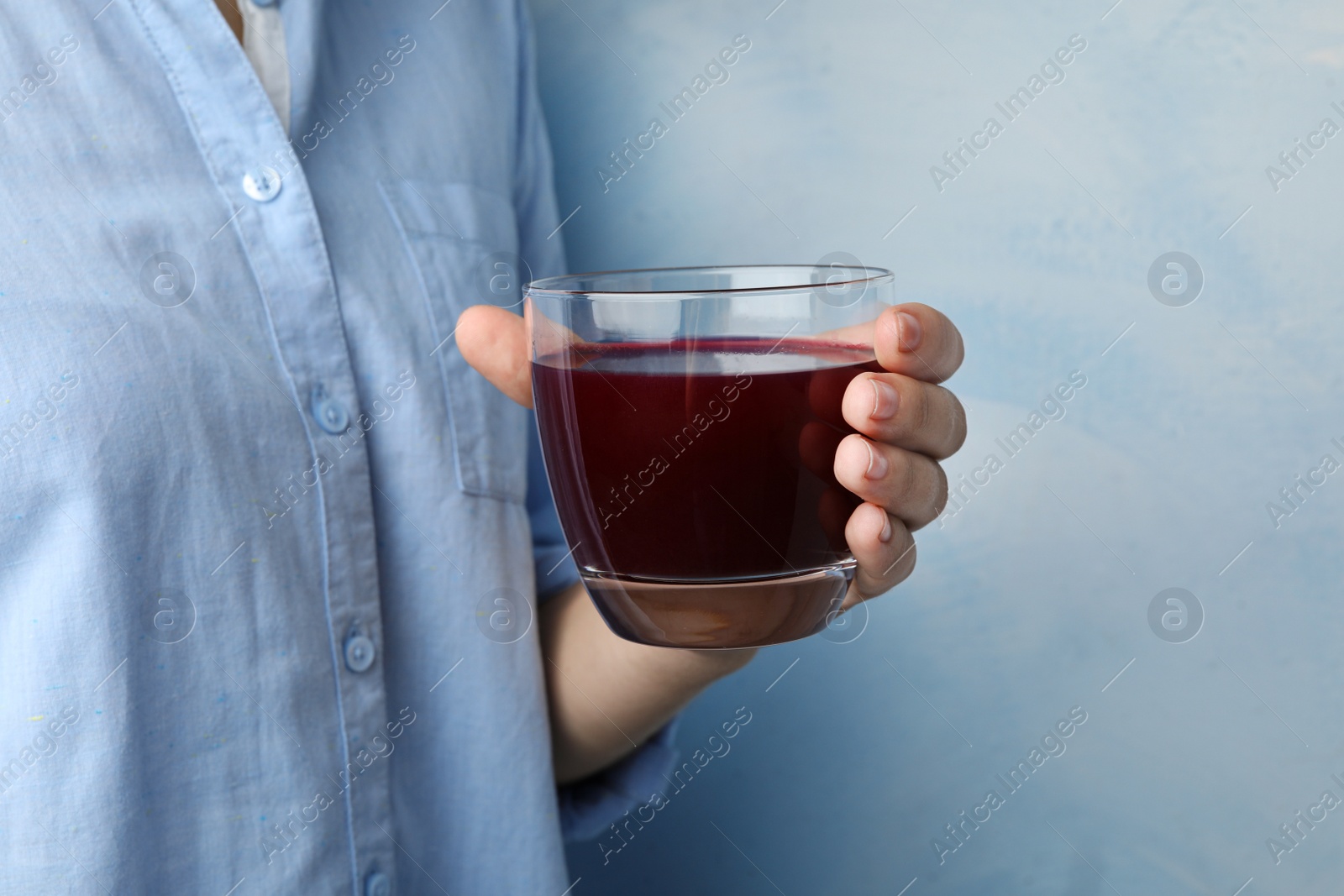 Image of Woman with glass of juice on light blue, closeup 