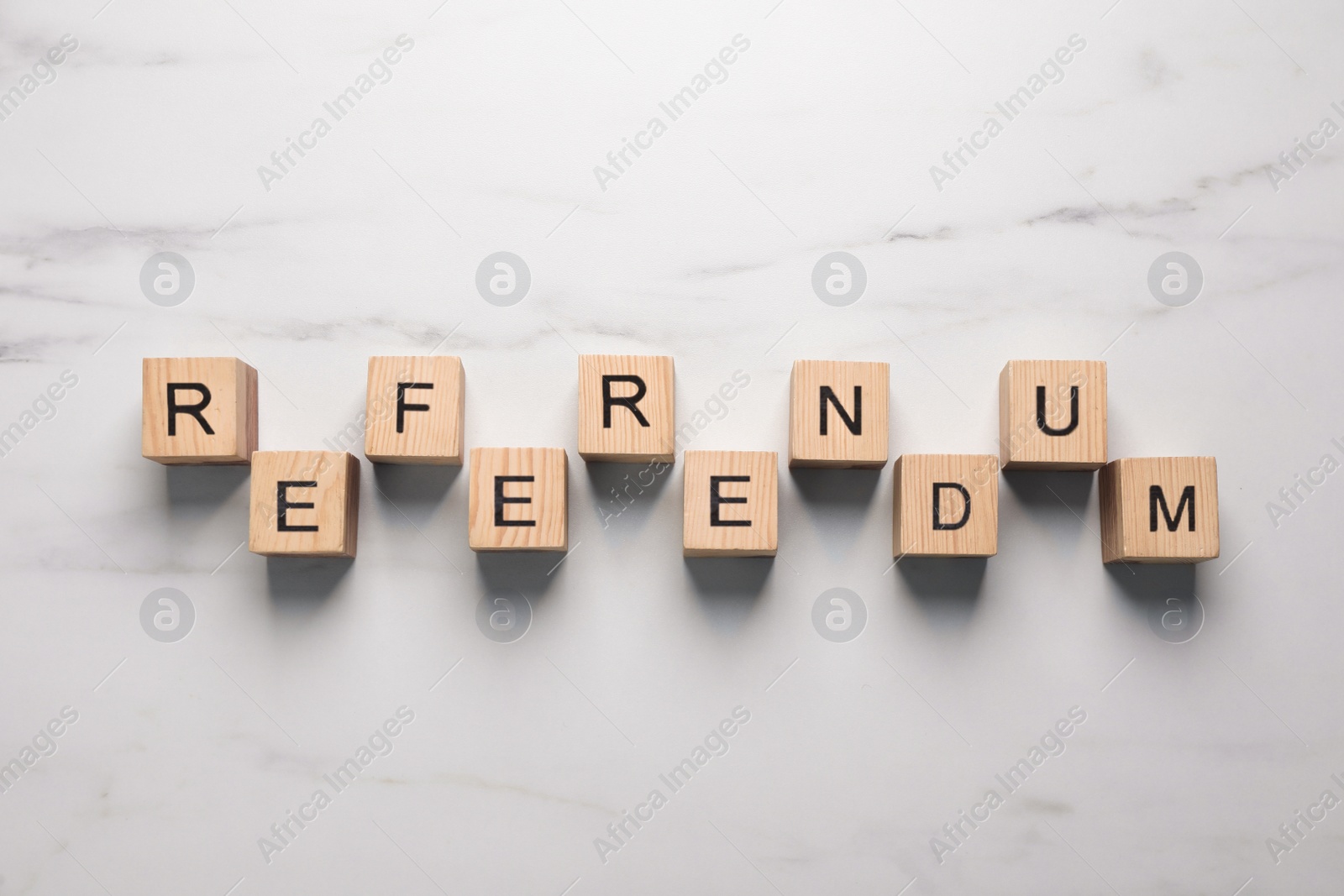 Photo of Word Referendum of wooden cubes on white marble table, flat lay