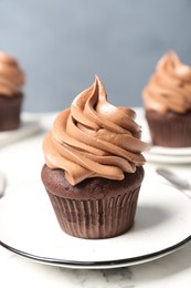 Photo of Delicious fresh chocolate cupcake on white marble table, closeup