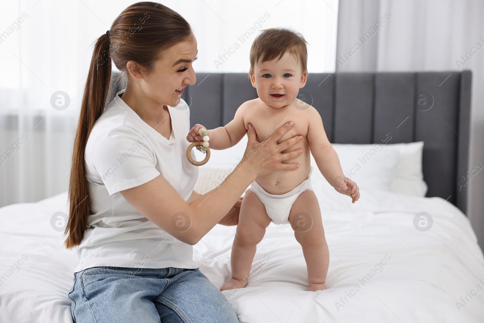 Photo of Mother playing with her baby on bed at home