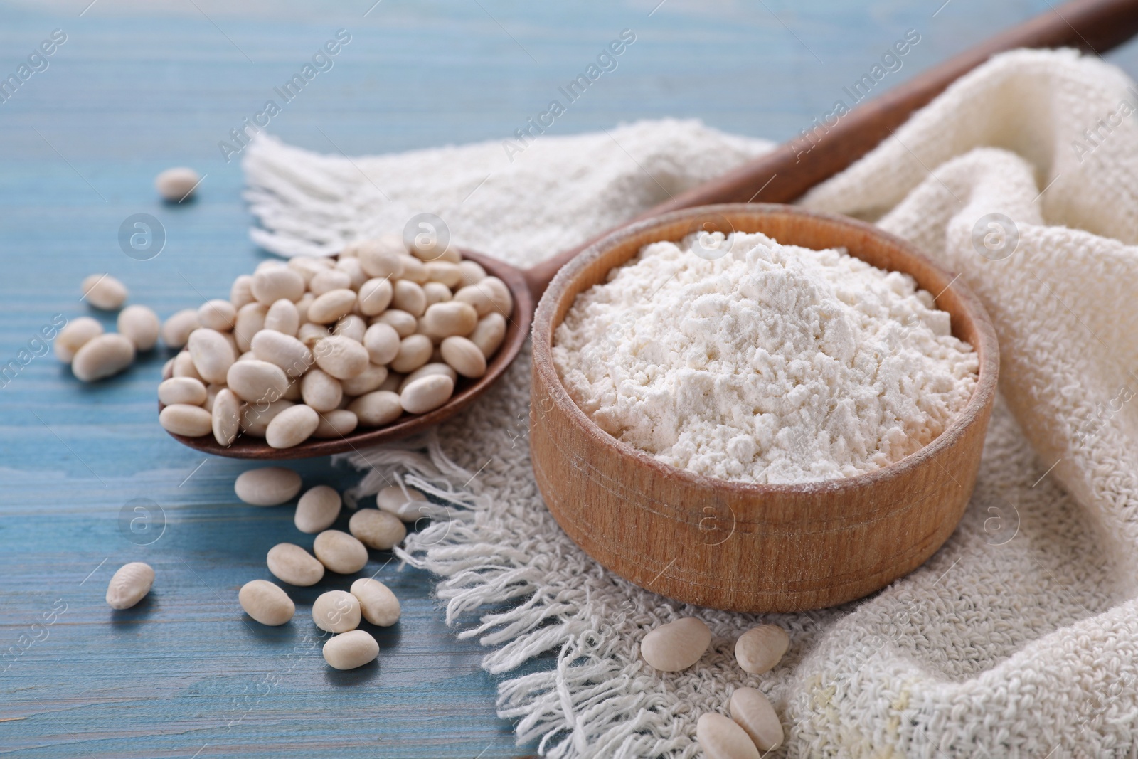 Photo of Kidney bean flour and seeds on light blue wooden table, closeup