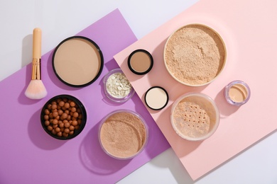 Flat lay composition with various makeup face powders on color background