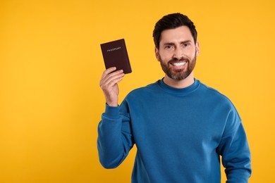 Photo of Immigration. Happy man with passport on orange background, space for text
